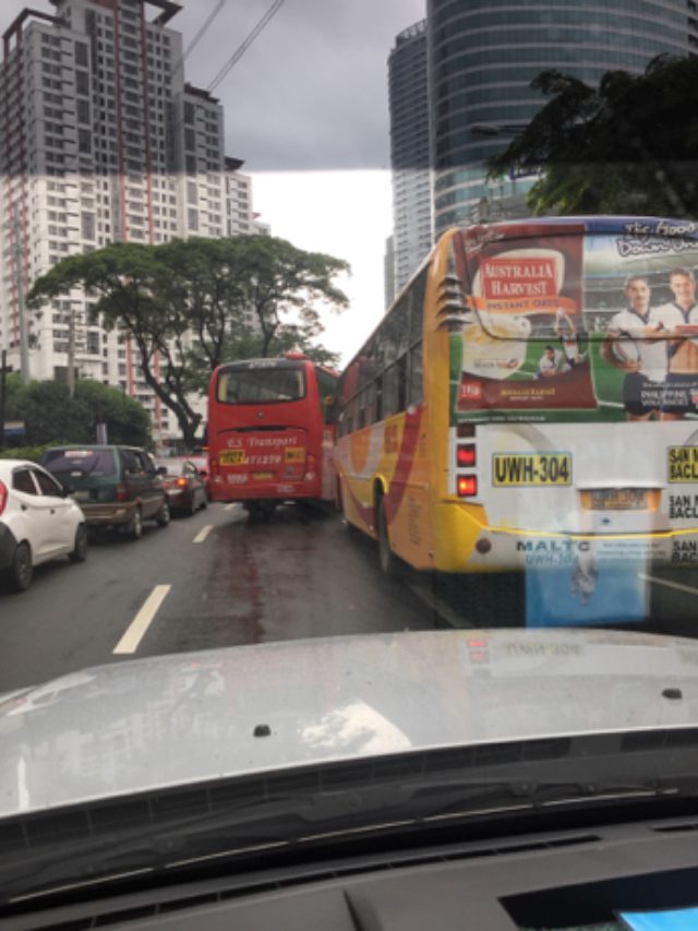 Private vehicles and buses in a street in Metro Manila. 