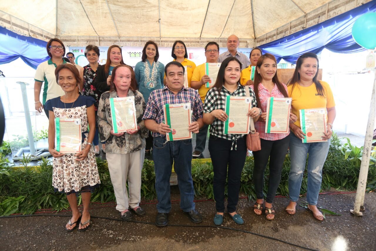 LAND TITLES. Vice President Leni Robredo, the Duterte administration's housing chief, hands over land titles to residents in Barangay Luz, Cebu City. Photo from the Office of the Vice President   
