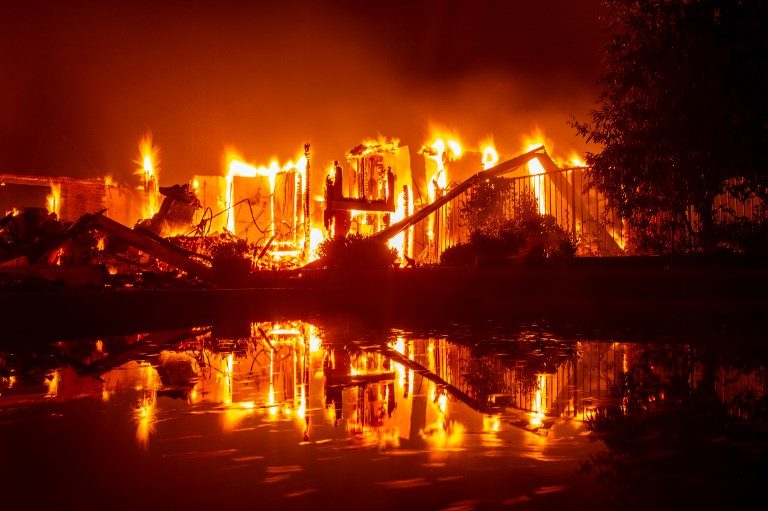 FIRE. A burning home is reflected in a pool during the Carr fire in Redding, California on July 27, 2018. Photo by Josh Edelson/AFP   