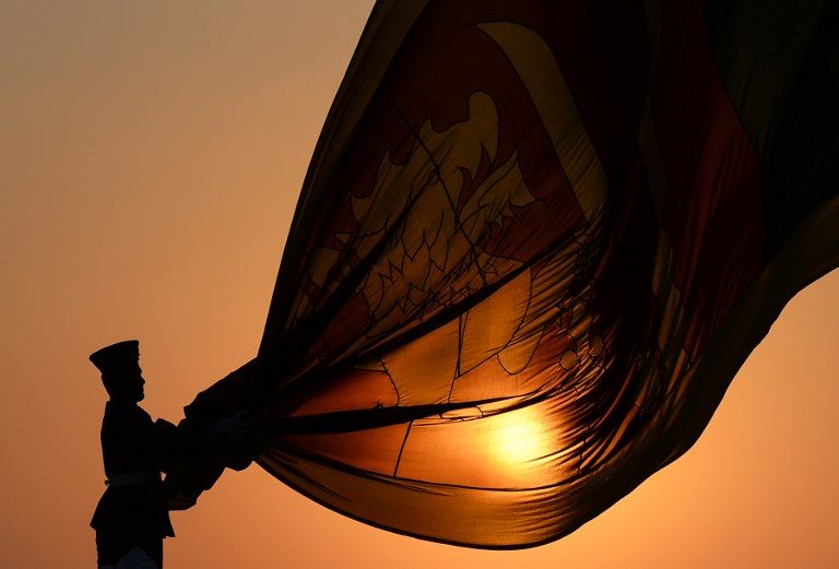 FLAG RETREAT. Sri Lankan Air force officers hold the national flag while it is lowered as part of a daily ceremony during sunset at the Galle Face Green promenade in Colombo on January 30, 2019. Photo by Lakruwan Wanniarachchi/AFP  