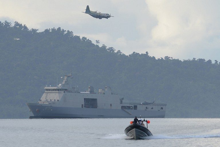 BALIKATAN. A Philippine Air Force C-130 cargo plane flies over Philippine navy sea lift vessel BRP Tarlac, while a speed boat loaded with US and Philippine marines sails during a simulation of a disaster drill as part of the annual joint Philippines-US military exercise at a sea port in Casiguran, Aurora province on May 15, 2017. Photo by Ted Aljibe/AFP   