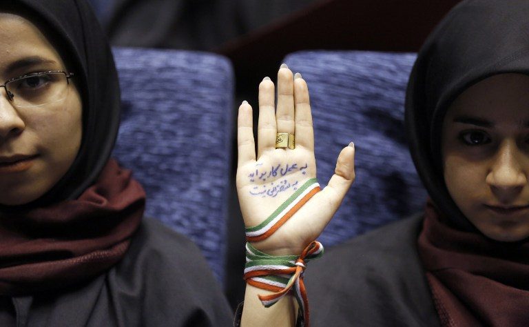 IRAN VOTES. A supporter of Iranian conservative presidential candidate and Tehran mayor Mohammad Bagher Ghalibaf attends a campaign rally in Tehran on May 14, 2017, with her hand wrapped with a band carrying the colors of the Iranian national flag and ink on her palm reading in Persian: 'With action not by speech you can finish the job and work.' Photo by Atta Kenare/AFP   