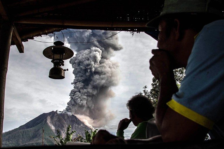 DORMANT FOR 400 YEARS. Villagers look on as Mount Sinabung volcano spews thick volcanic ash, as seen from Beganding village in Karo, North Sumatra province, on May 19, 2017. Sinabung roared back to life in 2010 for the first time in 400 years. After another period of inactivity, it erupted once more in 2013 and has remained highly active since. Photo by Ivan Damanik/AFP  