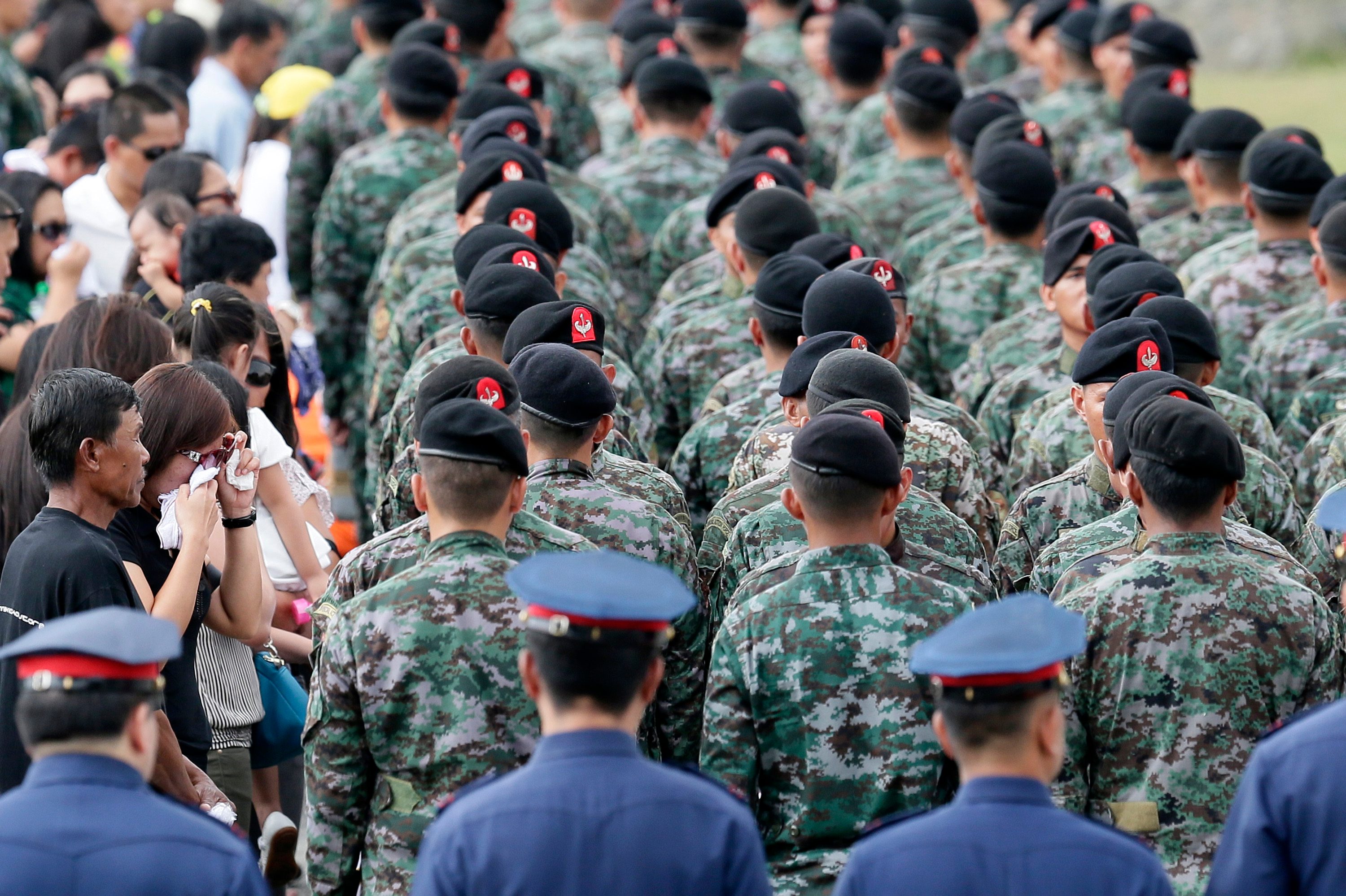 epa04592364 Relatives of killed elite Police Special Action Force pay their respect during arrival honors at Villamor Air Base, south of Manila, Philippines, 29 January 2015. Fighting between police and Muslim rebels in the southern Philippines has left at least 50 people dead, a police report said. Police were trying to arrest two suspected Jemaah Islamiyah terrorists in the town of Mamasapano in Maguindanao province, 960 kilometres south of Manila, when the clash erupted. The rebels belonged to the Moro Islamic Liberation Front (MILF), which signed a peace deal with the government in March, and to its breakaway faction the Bangsamoro Islamic Freedom Fighters, which opposed the agreement. EPA/DENNIS M. SABANGAN 