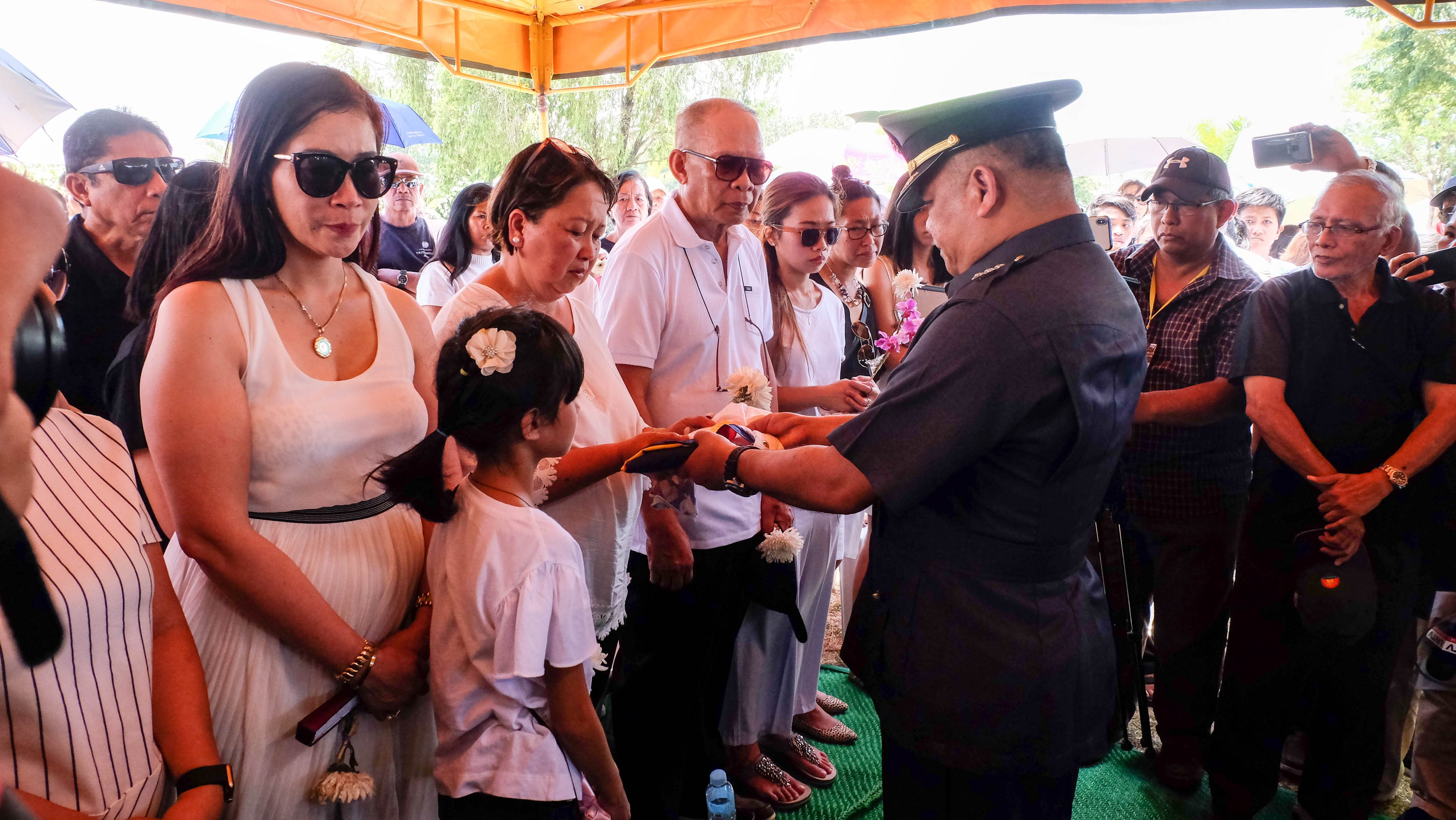 APOLOGIES. Colonel Claro Unson, PMA Deputy Dean of Academics hands the Philippine flag to Jazy Dormitorio, Darwin's mother, as husband retired Army Colonel William Dormitorio looks on. Photo by Bobby Lagsa/Rappler
  