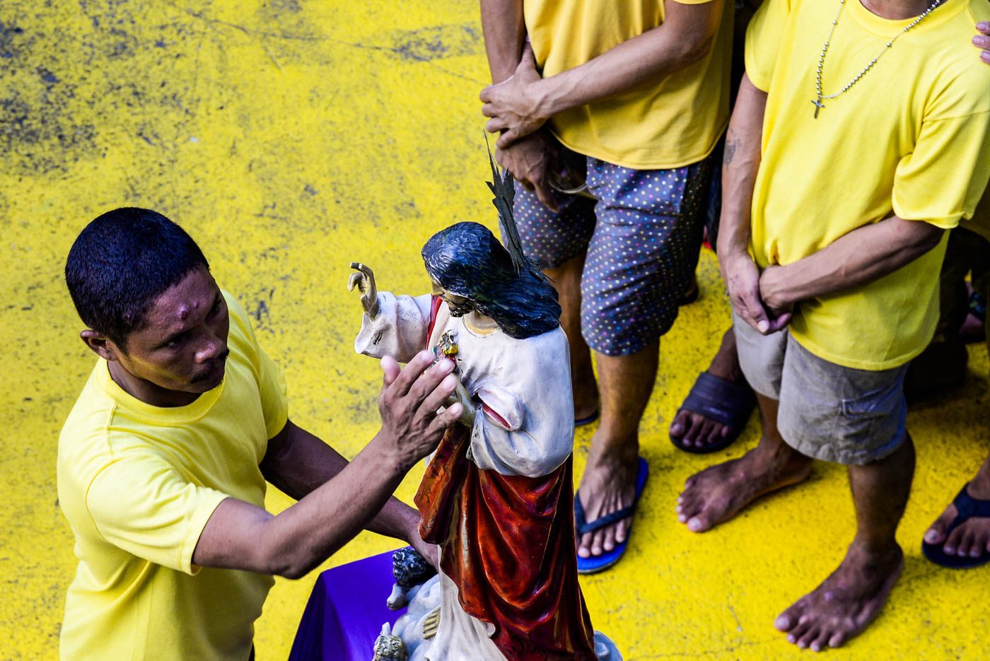 DEVOTION. While others line up to receive holy communion, an inmate touches an image of Jesus Christ. Photo by Maria Tan/Rappler  