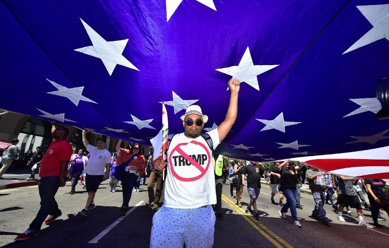 LABOR DAY PARADE. Carrying the US national flag, protesters march on May Day through downtown Los Angeles, California, on May 1, 2017. Photo by Frederic Brown/AFP   