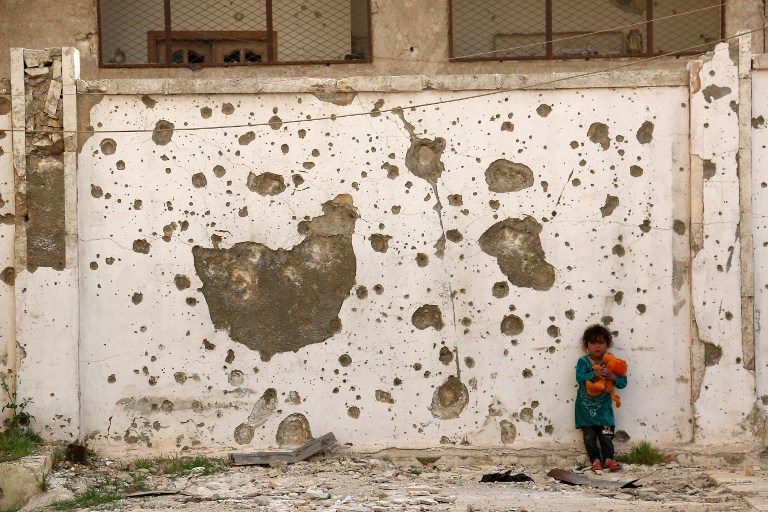 WAR IMPACT. A displaced Syrian girl plays with a toy in front of a damaged wall in the city of Azaz, situated on the border with Turkey, on April 30, 2017. Photo by Zein Al Rifai/AFP   