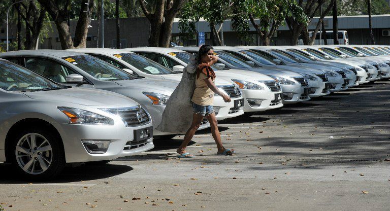 INCLUSIVE GROWTH? A scavenger walks in front of some of the hundred of new cars that will be used during the APEC summit. Photo by Jay Directo/AFP  