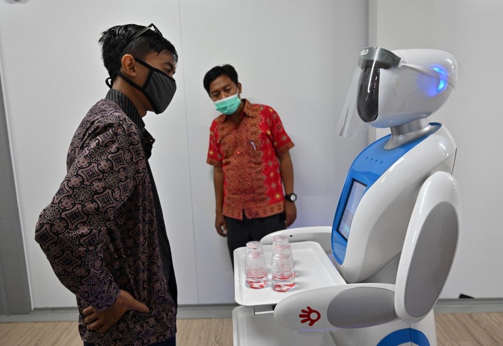 This picture taken on April 16, 2020 shows an Indonesian technician listening a robot known as Amy during a simulation on assisting medical teams in handling COVID-19 coronavirus patients at the Pertamina Jaya hospital in Jakarta. Photo by Adek Berry/AFP  