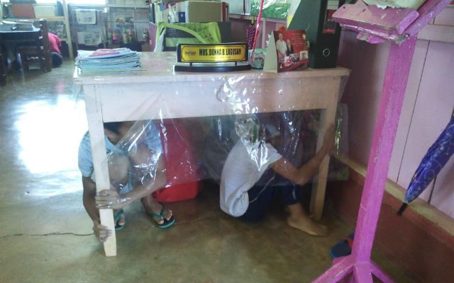 Students from Camp 9 Elementary School in Libona, Bukidnon do the duck, cover, hold in their classroom. Photo by Miriam Tuyor 