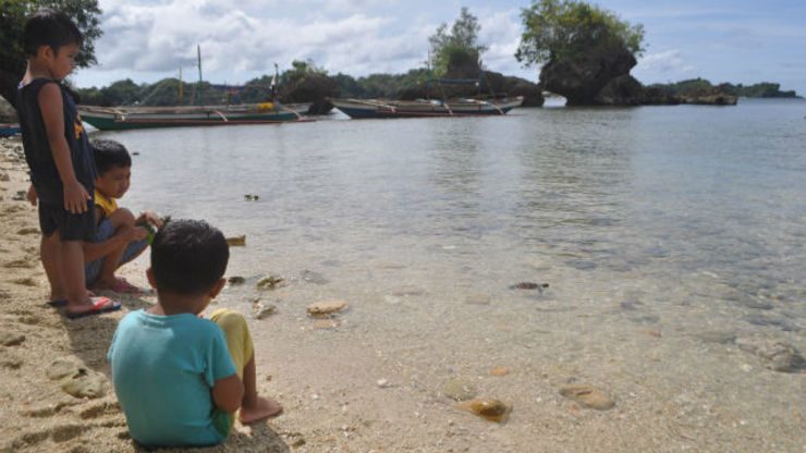 SAD GOODBYES. Boys looks at the baby turtles as they make their way back to the sea in Punta Lawi. Photo by Joselito Villasis