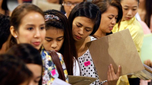 LABOR DAY. Filipino jobseekers fill-up application forms during a job fair inside SMX convention center on May 1, 2014. Photo by EPA. 