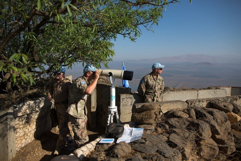 LOOKOUT POST. Members of United Nations Disengagement Observer Force (UNDOF) use binoculars to watch the Syrian side of the Golan Heights at Mount Bental in the Israeli occupied Golan Heights on August 31, 2014. Menahem Kahana/AFP