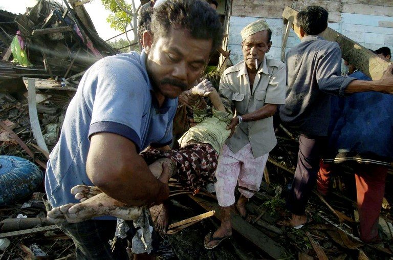 Sehari setelah tsunami, para relawan mengevakuasi korban dari reruntuhan bangunan. Foto oleh AFP