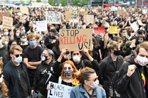 SOLIDARY PROTEST: Protesters hold placards at Alexanderplatz Square during a demonstration in solidarity with protests raging across the US over the death of George Floyd on June 6, 2020 in Berlin. Photo by Tobias Schawrz/AFP 