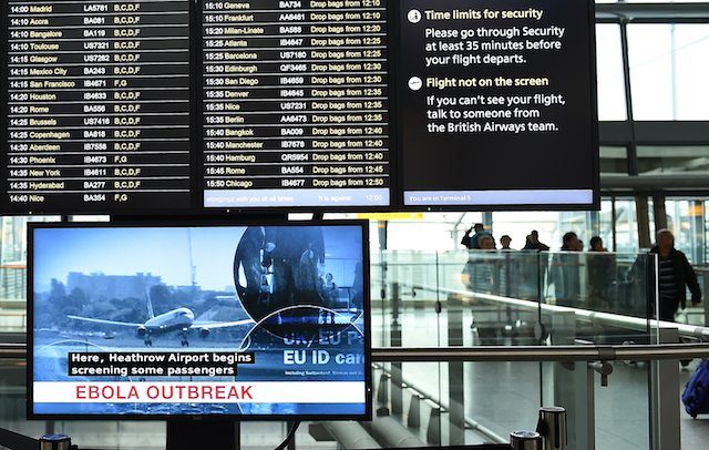 A Heathrow flight information screen is shown above a television screen reporting the Ebola outbreak at Heathrow Airport in London, Britain, 14 October 2014. Andy Rain/EPA