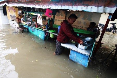 Pedagang memasak saat banjir menggenangi kawasan Tanjung Duren, Jakarta, Selasa (21/2). Foto oleh Rivan Awal Lingga/ANTARA 