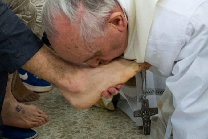 SYMBOL OF SERVICE. This handout picture released by the Vatican press office shows Pope Francis kissing the feet of a young offender after washing them during a Mass at the church of the Casal del Marmo youth prison on the outskirts of Rome as part of the Holy Thursday observance in 2013. File photo by AFP/Osservatore Romano   