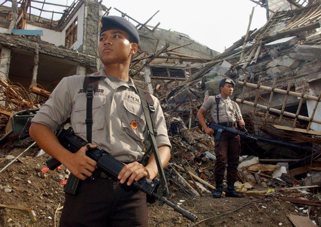 Policemen stand guard at bomb site during a purification ceremony in Kuta, Denpasar Bali, 15 November 2002, one month after a horrific bomb attack killing more than 190 people and injuring over 300 others. WEDA / AFP  