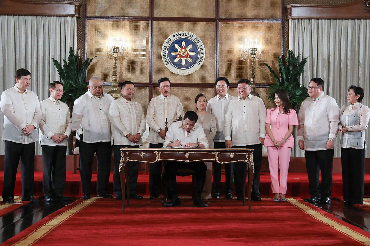LANDMARK LAW. President Rodrigo Roa Duterte leads the ceremonial signing of the Universal Health Care Act, with congressional leaders and some lawmakers who spearheaded the bill. Malacañang photo 