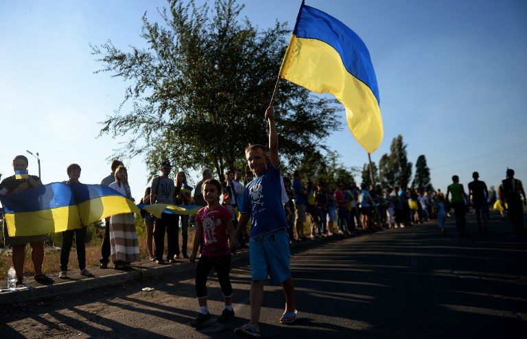 Ukrainian loyalists hold their flag as they rally at the last checkpoint on the eastern side of Mariupol on August 30, 2014. Francisco Leong/AFP