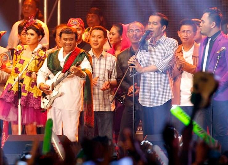 Dangdut star Rhoma Irama (2L) is accompanied on stage by then Jakarta Governor Joko Widodo (2R) during the New Year's Eve celebration at The Jakarta Night Festival, in Jakarta on December 31, 2013. Photo by Bagus Indahono/EPA 