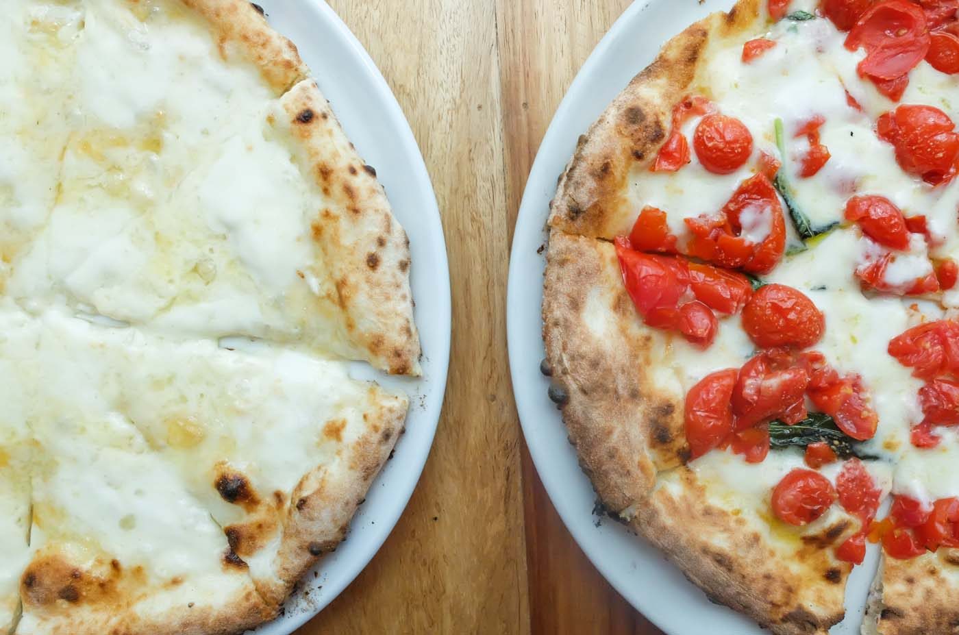 SIDE BY SIDE. The DOC vs the classic four-cheese pizza. Both are a feast for the palate, with an option to enjoy the latter with a drizzle of honey on top  