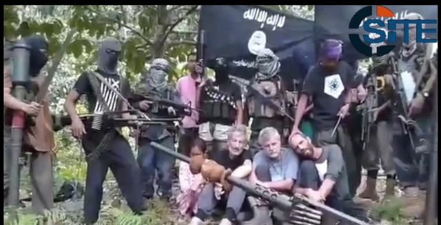 CAPTIVE. The hostages are seen surrounded by masked gunmen in a jungle setting. Video screengrab from SITE Intelligence Group 