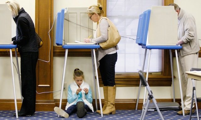 Ella Duane, 9, waits under the booth as her mother Laura Duane votes at the Broadway Baptist Church in Louisville, Kentucky, USA, 04 November 2014. Mark Lyon/EPA