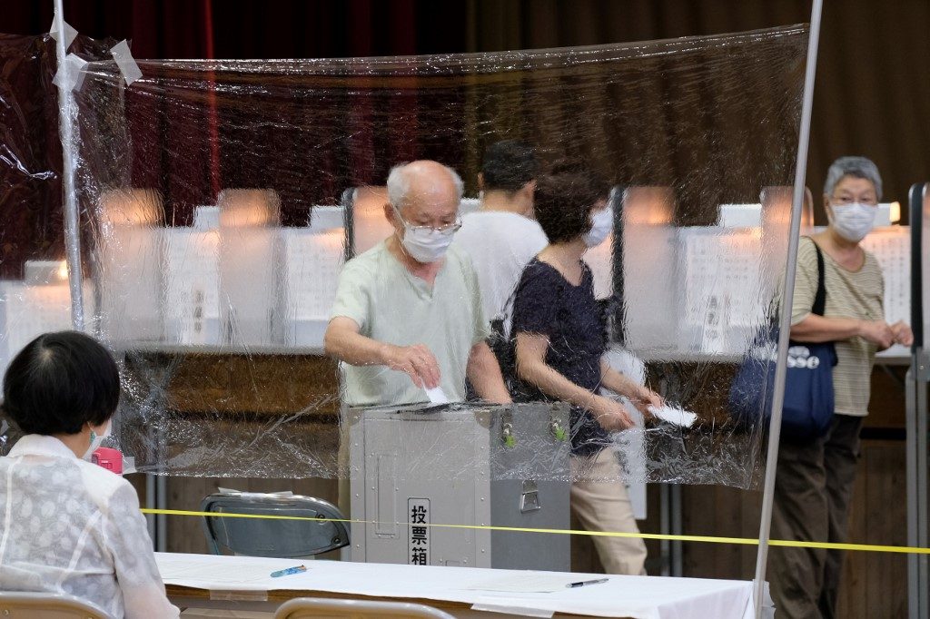 TOKYO VOTE. A man casts his vote for the Tokyo gubernatorial election behind a sheet of plastic as a precaution at a polling station in Shinjuku area in Tokyo on July 5, 2020. Photo by Kazuhiro Nogi/AFP 