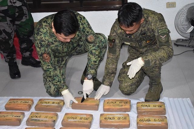 UNPACKING. Brigadier General Gilbert Cruz (left) leads in opening cocaine bricks found in Lingig, Surigao del Sur. PNP photo   