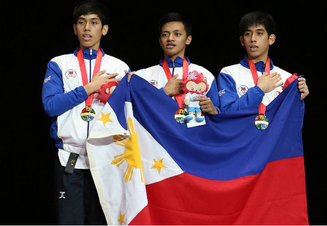 Dustin Jacob Mella, Rodolfo Reyes Jr and Raphael Enrico Mella hold their nation's flag after receiving their gold medals. Singapore SEA Games Organising Committee/Action Images via Reuters  