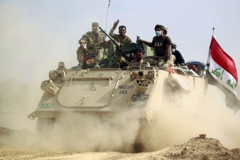 FIGHT ADVANCES. Iraqi forces on an armored personnel carrier (APC) advance in the Jurf al-Sakhr area, north of the Shiite shrine city of Karbala on October 30, 2014, after they retook the area from Islamic State (IS) group jihadists over the weekend after months of fighting the regain the ground. Haidar Hamdani/AFP