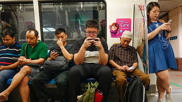 FALSE REPORTS. Singaporeans check their phones during their commute. AFP photo  