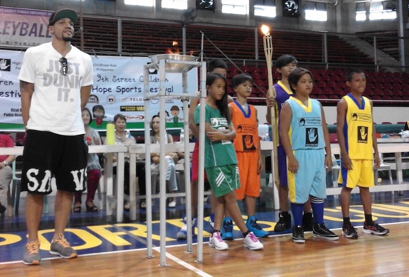 LIT TORCH. The young players and basketball player Harvey Carey stand beside the games' torch during the opening of the Hope Sports Fest. Photo by Bea Orante/Rappler 