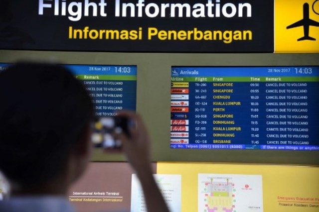 Seorang calon penumpang melihat pap an informasi di Bandara International Ngurah Rai, Bali, Selasa (28/11). FOTO oleh JUNI KRISWANTO / AFP 