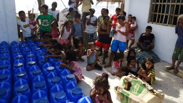 BASIC NEEDS. A month after Yolanda, families in Culasi receive relief goods which included purified water and food packs from Anthony and his group.   