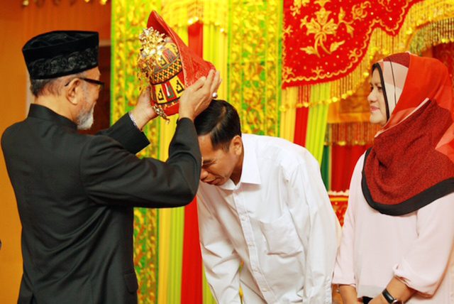 ACEH VISIT. Malik Mahmud, the Aceh cultural leader, placing a customary Acehnese headdress on President Joko Widodo, with the first lady, Iriana, beside him during their visit to Banda Aceh on March 9, 2015. Photo released by Aceh government/Rappler  
