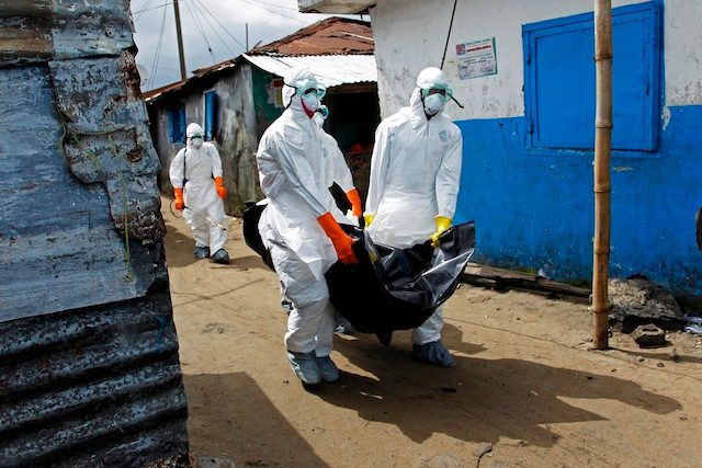 Liberian health care workers on an Ebola burial team collect the body of an Ebola victim in Westpoint, Monrovia, Liberia, 13 September 2014. Ahmed Jallanzo/EPA