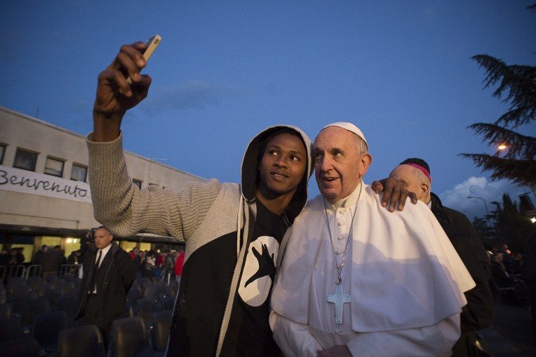 Paus Francis berpose 'selfie' bersama seorang migran saat kunjungannya ke pusat pengungsian di Castelnuovo di Porto, sebelah utara kota Roma, Italia. Foto oleh STR / AFP 