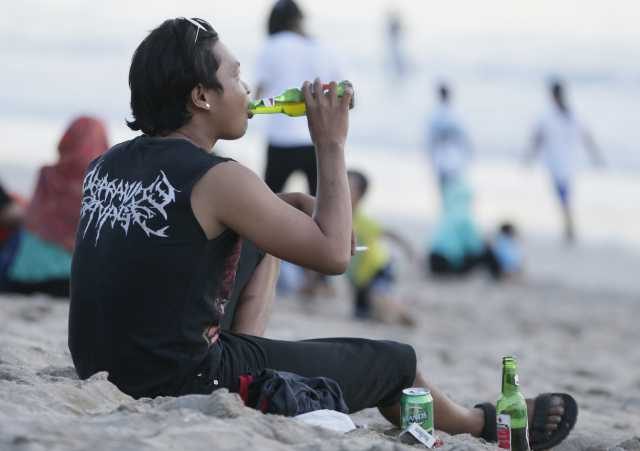 MINUMAN BERALKOHOL.  Seorang turis sedang minum bir di pinggir Pantai Kuta, Bali.  Foto oleh Made Nagi/EPA    