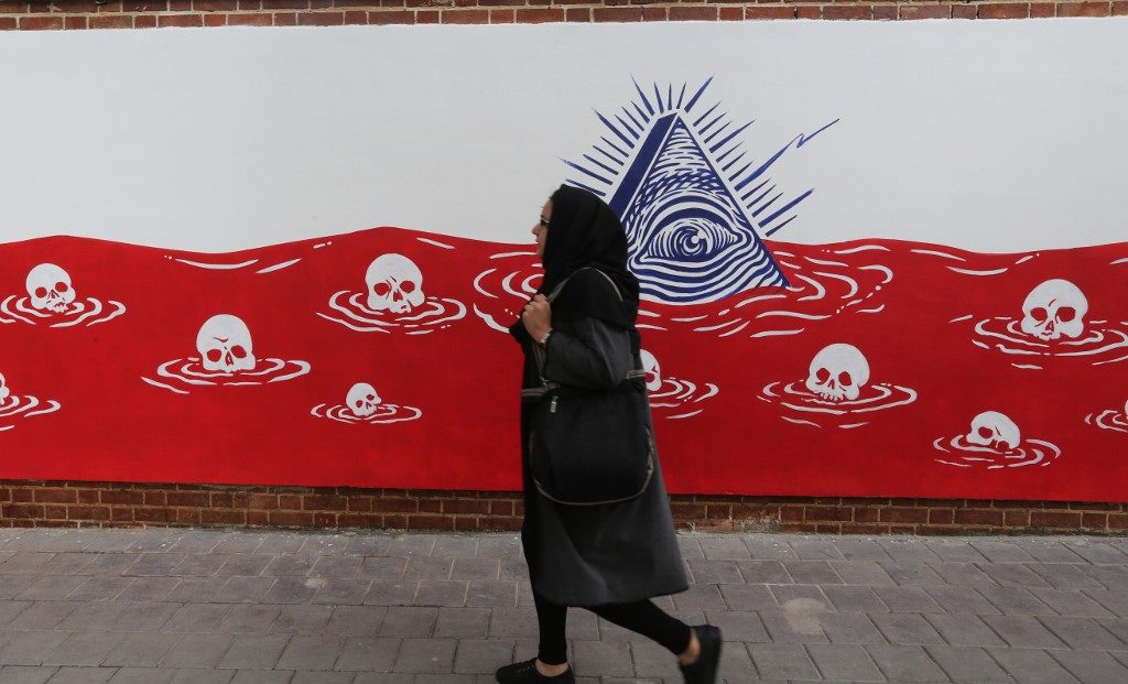 SOAKED IN BLOOD. An Iranian woman walks past a new mural painted on the walls of the former US embassy in the capital Tehran on November 2, 2019. Photo by Atta Kenare/AFP 