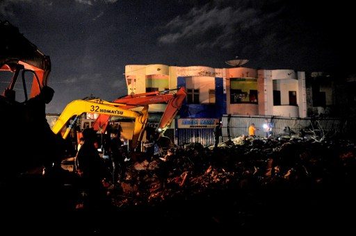 Evakuasi terus dilakukan meski malam telah larut. Sebab korban yang mungkin tertindih timbunan puing tak bisa menunggu. Foto oleh
CHAIDEER MAHYUDDIN / AFP 