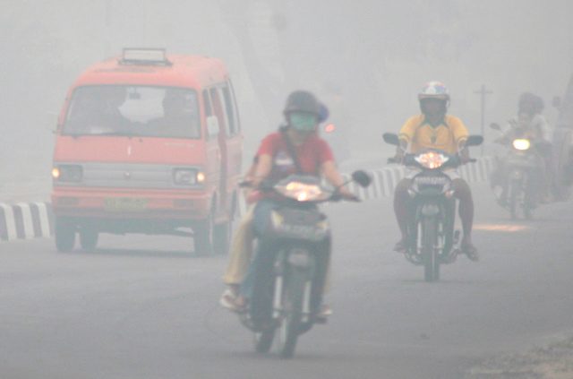 KABUT ASAP. Pengendara motor melalui daerah yang diselimuti kabut asap di Palangkaraya, Kalimantan Tengah, 18 Oktober 2006. Foto oleh Seto Ramdani/EPA 