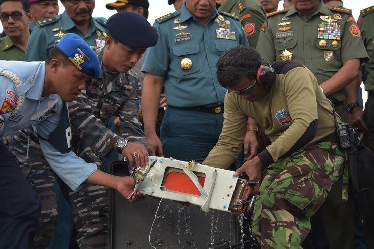 Indonesian officers move the FDR (Flight Data Recorder) (C) of the AirAsia flight QZ8501 into a suitable protective transportation case in Pangkalan Bun after it was retrieved from the Java Sea on January 12, 2015. Photo by Adek Berry/AFP 
