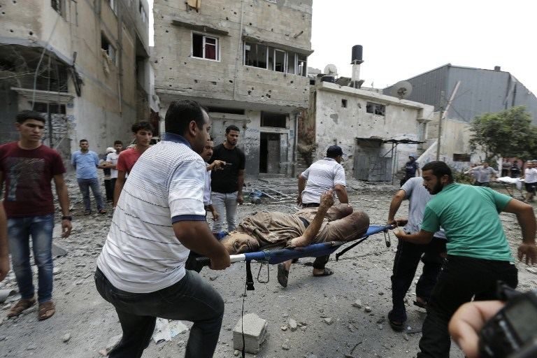 Palestinian rescuers evacuate a body following an Israeli military offensive on the Shejaiya neighborhood between Gaza City and the Israeli border, which has left more than 50 people dead in a blistering bombardment which began overnight, medics said on July 20, 2014. Mohammed Abed/AFP