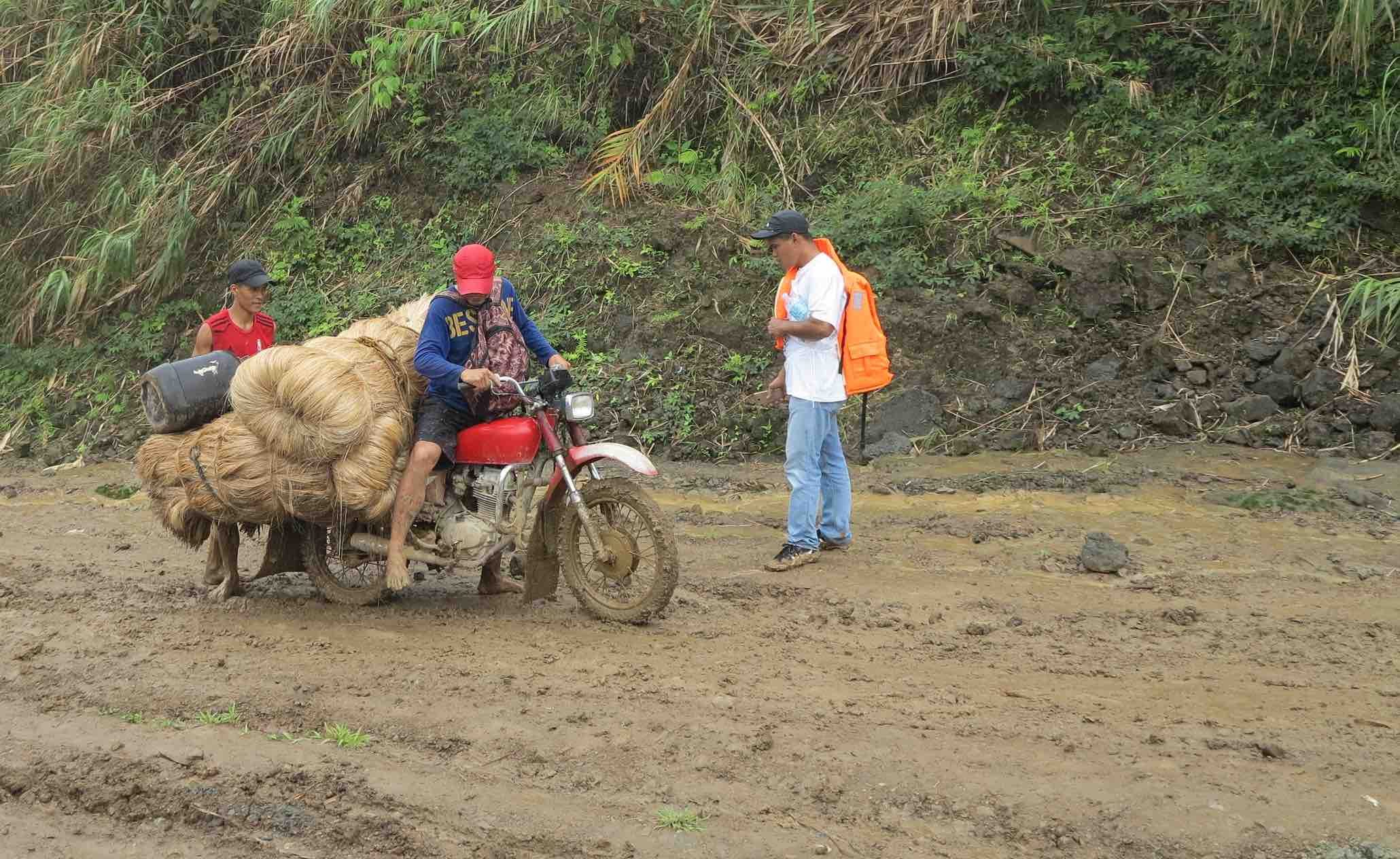 STRUGGLE ON THE ROAD. These two men struggle to bring their abaca to the town market. It has been raining for days and they need the income, so they risked the trip. 