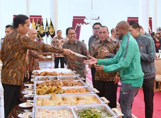 MAKAN SIANG. Presiden Joko "Jokowi" Widodo memberikan piring kepada kapten timnas Boaz Solossa (kanan) saat akan mengambil makanan untuk santap siang di Istana Kepresidenan pada Senin, 19 Desember. Foto dari Biro Pers Setpres 