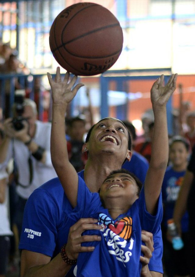 Jordan Clarkson helps a young child in Tondo make a basket. Photo by Noel Celis/AFP 